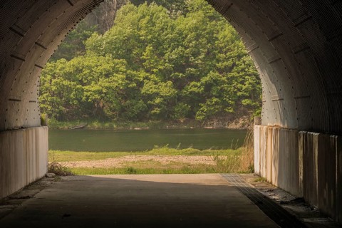 View of small boat on far tree lined river bank seen through a concrete underpass in South Korea