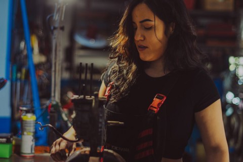 Focused mechanic female repairing a scooter engine part in a workshop, a complete tool panel in