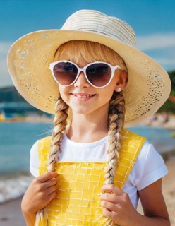 KI generated, An 8 year old blonde girl with sunglasses and a straw hat is on holiday on the beach