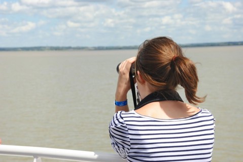 Girl looking at the river with binoculars