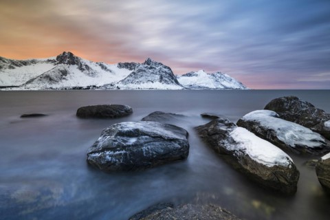 Rocky coast at the fjord with snow-covered mountains at sunset, Steinfjorden, Tungeneset,