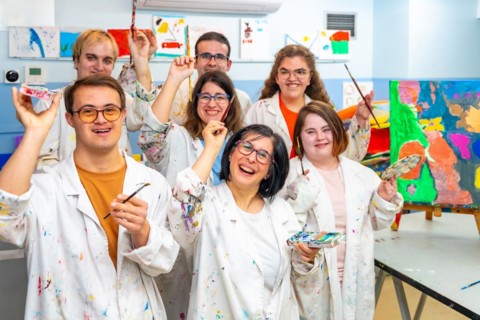 Portrait of a group of happy disabled people with dirty coats in a painting class