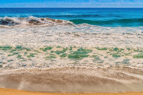 Seascape of whitecaps and waves as tide rolls in to shore on beautiful winter morning under partly