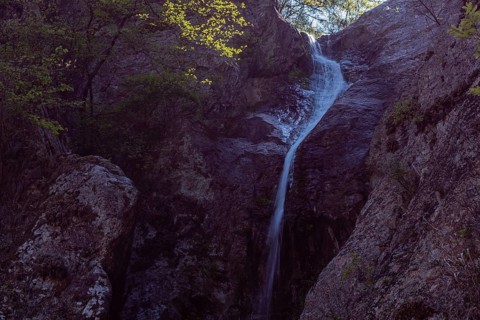 Water cascades down a rocky surface amid twilight hues, in South Korea