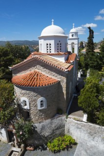 View of a church with a white dome and terracotta roofs against a clear blue sky, Holy Monastery of