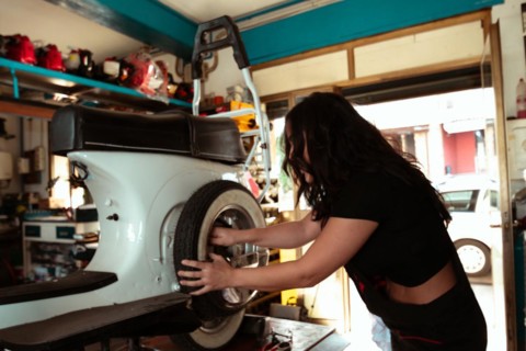 Hispanic young sensual long haired brunette woman Mechanic adjusting a tire on a vintage italian