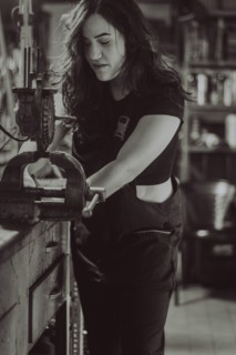 Craftswoman engaged in work using a vise on a bench in workshop, real women performing traditional