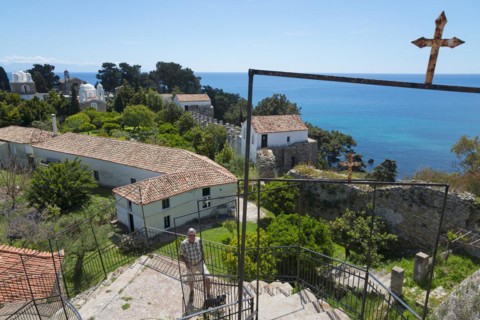 View of a religious site overlooking the sea, a person stands at the railing, view from the vantage
