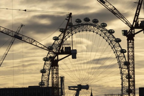 London Eye or Millennium Wheel tourist observation wheel at sunsetwith industrial cranes and
