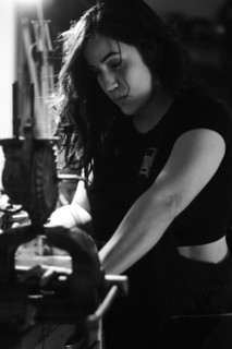 Hispanic latino long haired brunette sexy woman mechanic examining a car part in a well-equipped