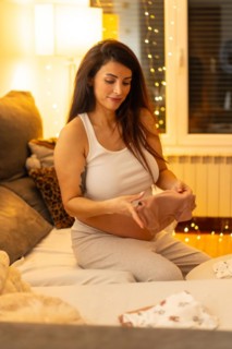 Vertical portrait of a tranquil scene of a beauty pregnant woman folding clothes preparing bag for