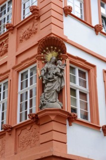 Baroque statue on a terracotta-coloured house facade with golden rays, Heidelberg,