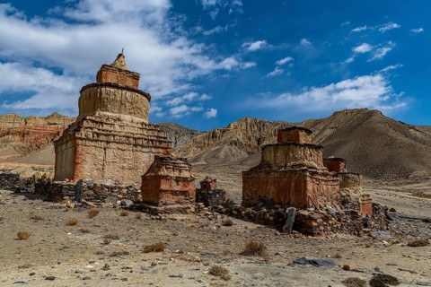 Colourfully painted Buddhist stupa, in a eroded mountain landscape, Kingdom of Mustang, Nepal, Asia