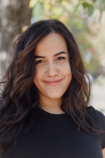 Outdoor image of a confident Cheerful hispanic young woman smiling in a black shirt with a relaxed