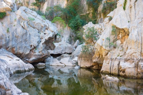 Torrent de Pareis, calm water surface in a riverbed of a mountain stream surrounded by impressive,