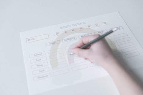 Diabetes log, daily log of food and insulin administration, food log, hand of a child holding a pen
