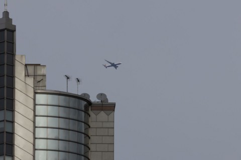 Airbus A319-100 aircraft of British airways in flight over a city skyscraper building, London,