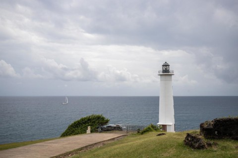 White lighthouse on a steep coast. Dramatic clouds with a view of the sea, pure Caribbean at Le