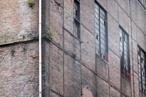 Old industrial building with weathered brick wall and rusty window frames