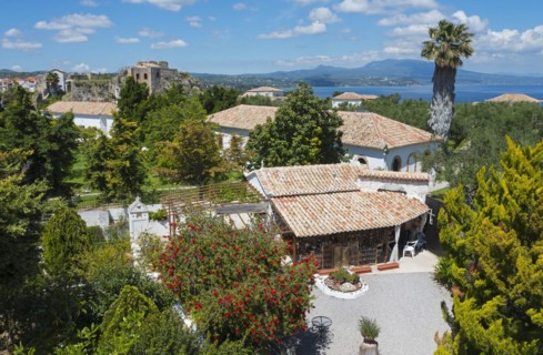 Monastery with buildings with terracotta roofs, sea view and a castle in the background, on the