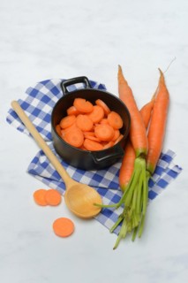 Carrot slices in pots and wooden spoon, carrot (Daucus carota)