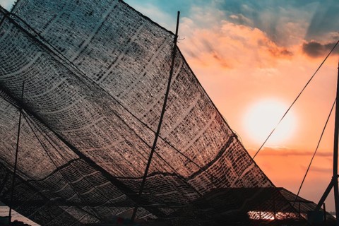 Close up of fishing nets hanged to dry and backlit by the sunset light in Mekong Delta, Vietnam,