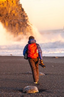 Adventurous photographer woman in winter in Iceland visiting the Reynisfjara Black Sand Beach