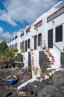 Typical white houses with small gardens on lava rock, on the promenade of Puerto del Carmen,