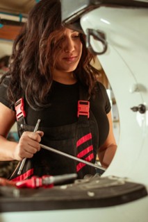 Hispanic young sensual long haired brunette Female mechanic attentively working with a screwdriver