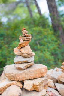 Carefully stacked, slightly red stones form a stone figure, cairn, waymark, marker in the forest,