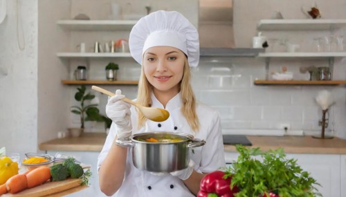 AI generated, An attractive blonde cook in the kitchen of a hotel tastes a vegetable soup