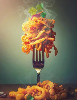 Fast food nocive nutrition concept with a fork holding a pile of oilish foodstuffs on top.