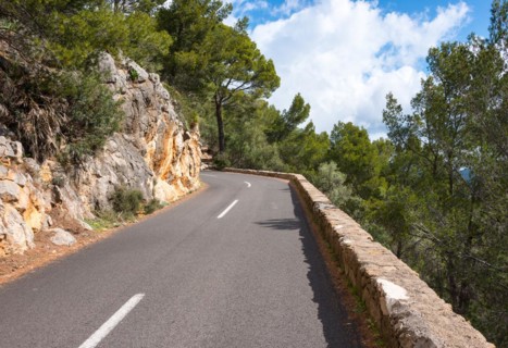 Winding, very narrow mountain road on a steep rocky slope, lined with rocks (limestone) and