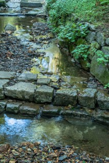 Closeup of shallow man made stream cascading over flat stones on sunny summer day in South Korea