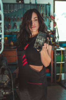 Hispanic Woman with mechanical part in hand, concentrating on her work in a workshop, a complete