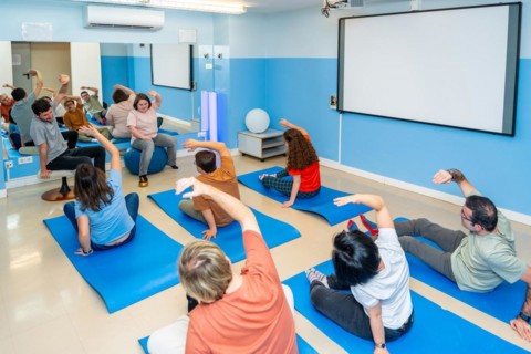 Elevated rear view of a group of male and female disabled people stretching during yoga class