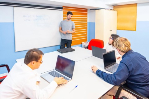 People with special needs attending a IT class using laptop while teacher explain using white board