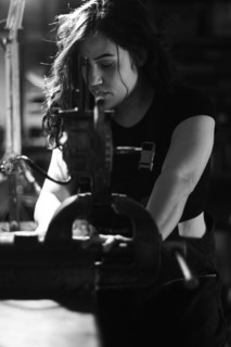 Hispanic latino long haired brunette sexy woman mechanic examining a car part in a well-equipped