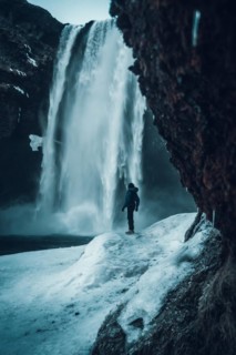 Photographer woman in winter in Iceland visiting Skogafoss waterfall