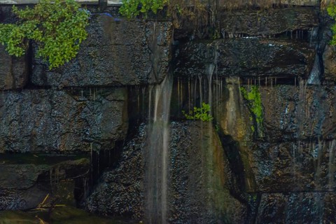 Close-up of water trickling down a mossy stone wall creating a serene atmosphere, in South Korea