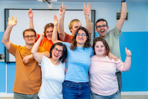 Happy people with special needs posing after gymnastic class laughing at the camera and raising