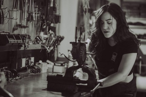 Craftswoman focused on a task at her workbench amid various tools, real women performing