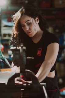 Female technician in the midst of workshop activity, skillfully fixing a component with focus, a