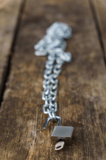 Shiny chain with padlock unlocked on a wooden table in a park with a selective focus