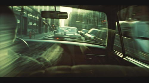 Looking through a car's rearview mirror at city traffic bathed in sunlight, AI generated