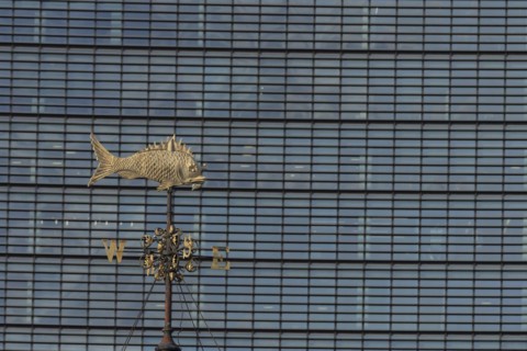 Fish weather vain in front of a high rise office skyscaper building, City of London, England,