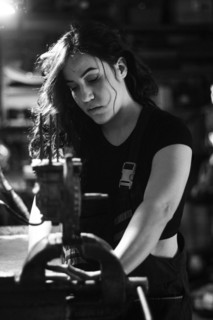 Hispanic latino long haired brunette sexy woman mechanic examining a car part in a well-equipped