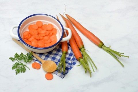 Carrot slices in pot and wooden spoon, carrot (Daucus carota)