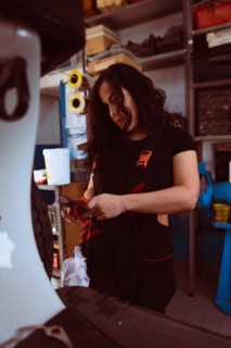 Hispanic young sensual long haired brunette Mechanic with a draper applying detail to a classic