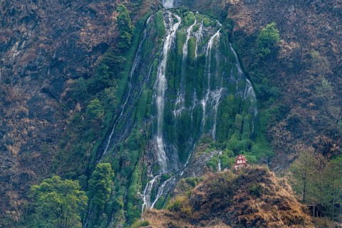 Little stupa undeaneath a huge waterfall, along the highway to Jomsom, Nepal, Asia